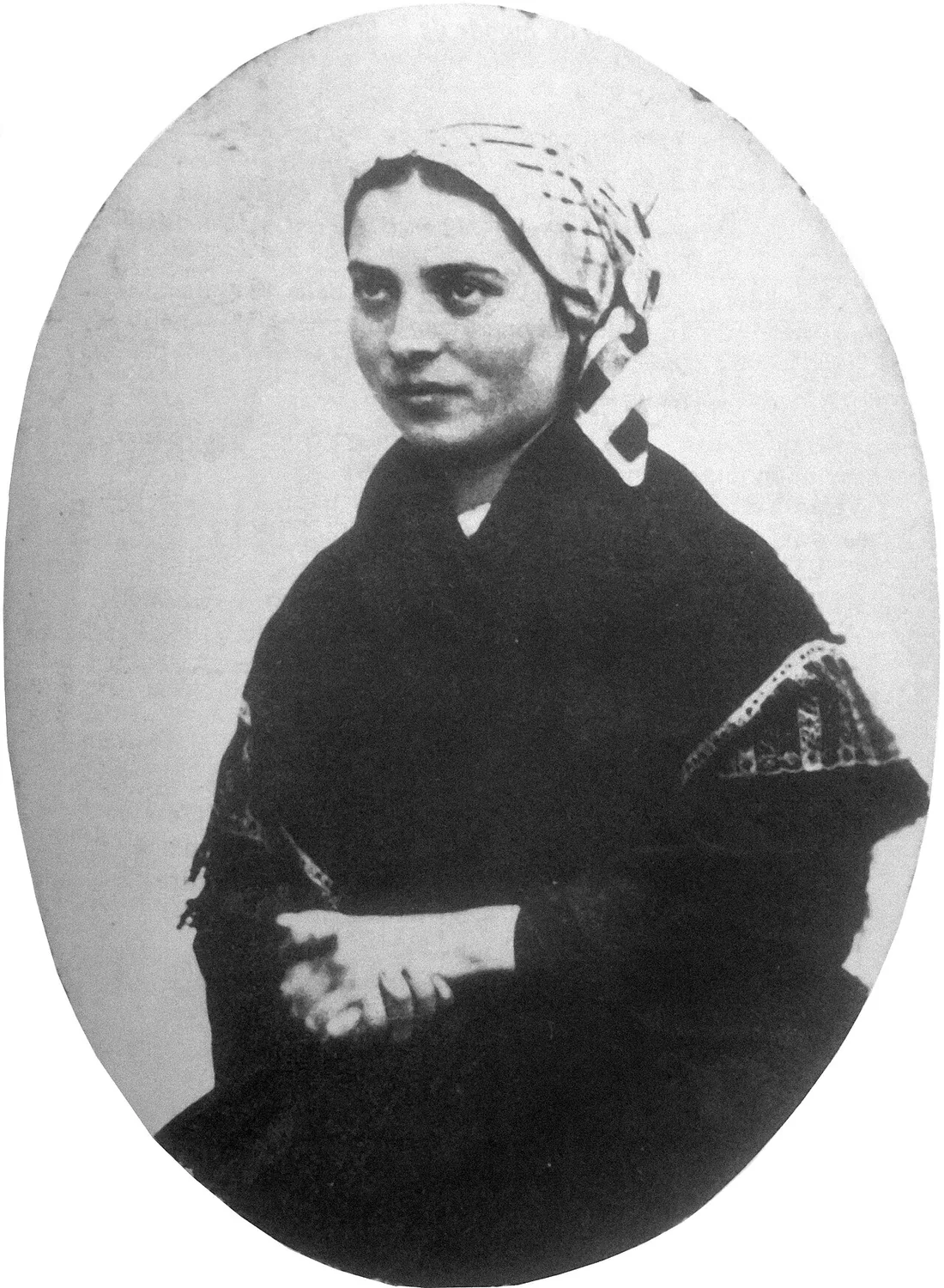 Sainte Bernadette Soubirous : Photographie ancienne de Bernadette Soubirous assise, tenant un livre.
